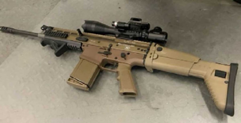 Coos County Sheriff Office Photo of a black and tan seized stolen assualt rifle, with a scope and magazine photographed on the floor.