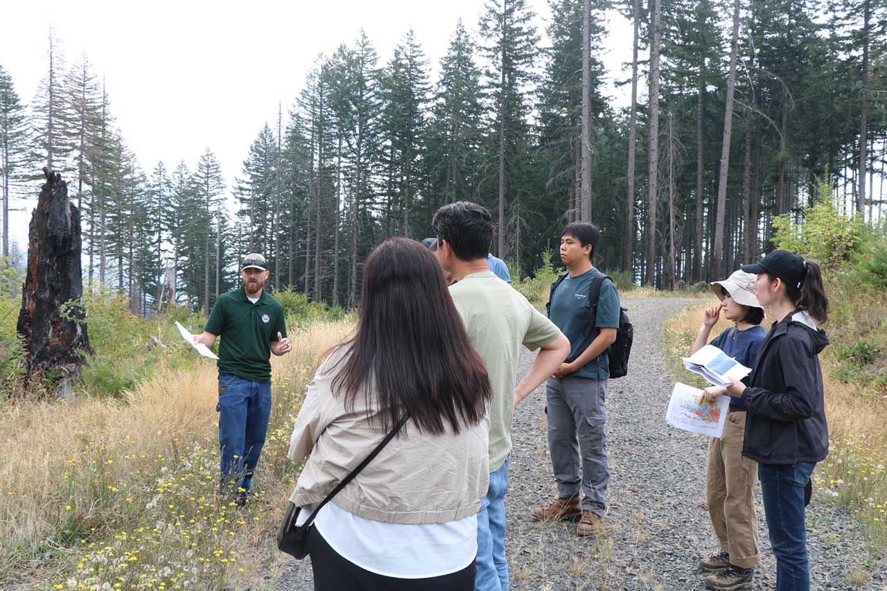 Kyle Kaupp, ODF’s Santiam Unit Manager, discusses burn severity and salvage logging operations in the Stout Creek Restoration area in the Santiam State Forests with a group of South Korean forest researchers.